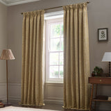 Saffron-gold pencil pleat curtains in Acorn tonal jacquard fabric, hung from a bronze pole beside a window in a living room setting.