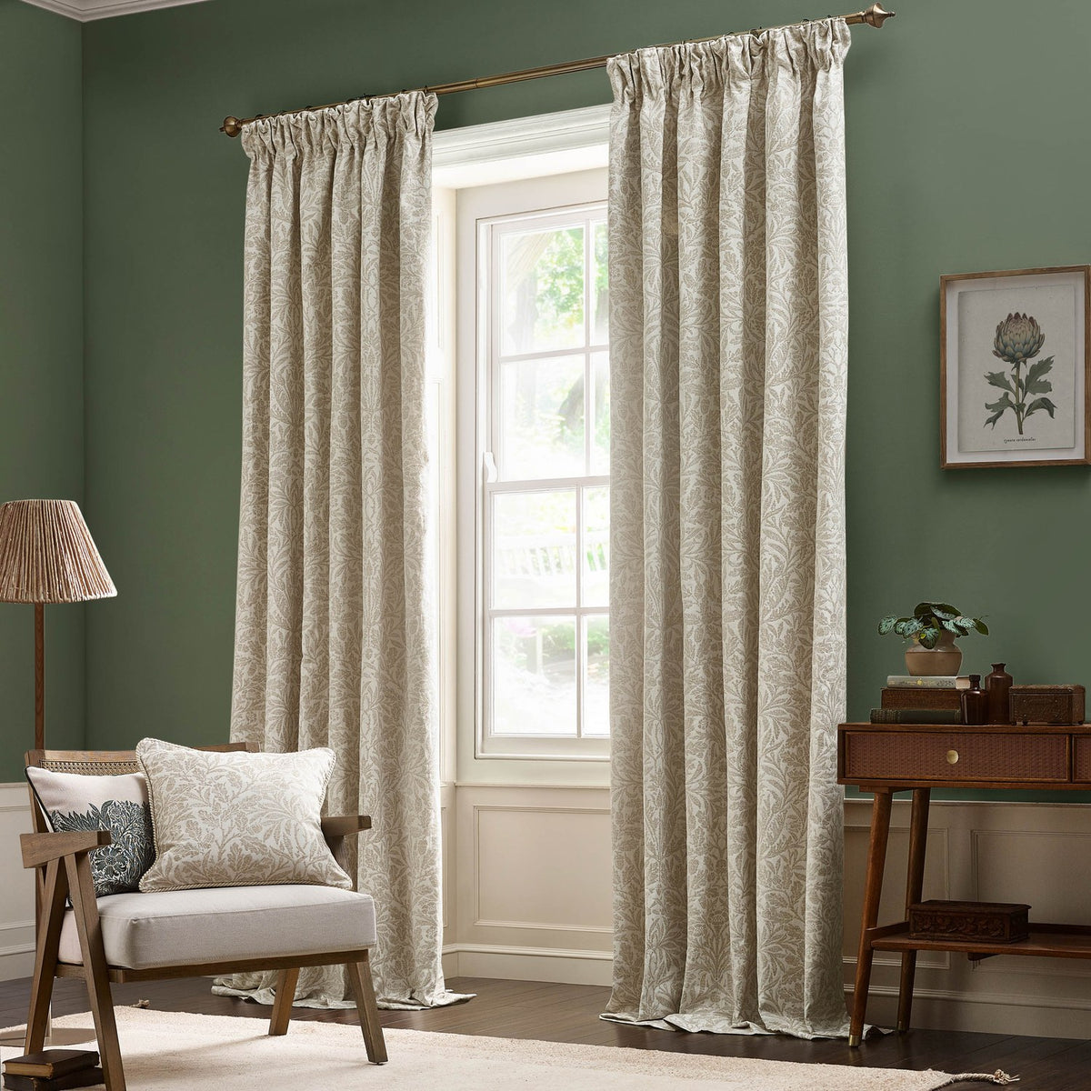 Acorn Tonal Jacquard pencil pleat curtains in Willow, cream leaf-patterned fabric with pencil pleat heading, shown hanging beside a window in a green living room.