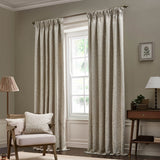 Acorn Tonal Jacquard Linen Pencil Pleat Curtains in beige, floor-length with pencil pleat heading, shown framing a window in a living room with matching cushion on an armchair.