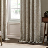 Acorn Tonal Jacquard Linen pencil pleat curtains in beige with woven acorn and oak leaf pattern, shown pooling on the floor beside a window in a living room.