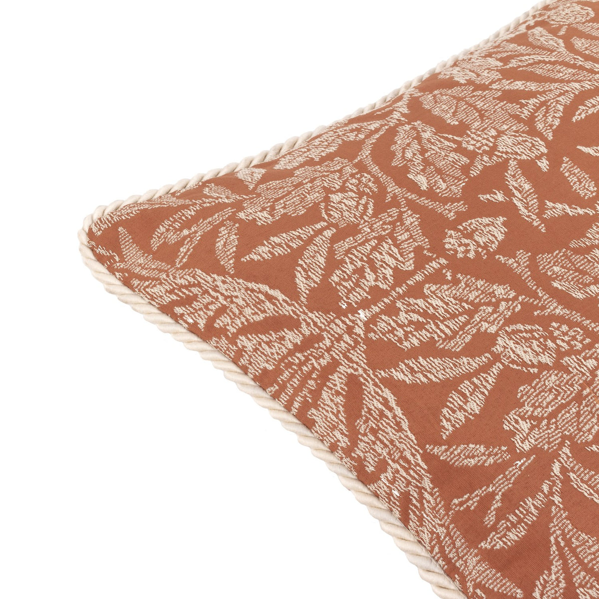 Acorn Tonal Jacquard Polyester Cushion in brick orange, close-up of the corner showing the woven cream oak leaf and acorn pattern with a matching cream twisted cord edge trim.