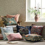 Square patterned cushion in brick-orange jacquard fabric with woven cream acorn and oak leaf motif, shown among William Morris print pillows in a living room setting.