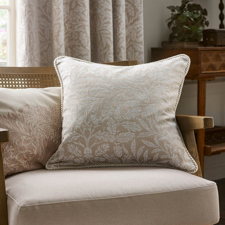 Square Acorn Tonal Jacquard Linen Cushion in cream with woven leaf and acorn pattern and corded edge trim, shown on an armchair in a living room setting.