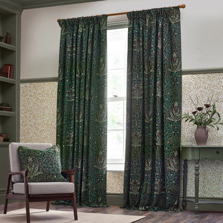 Pencil pleat curtains in the Acorn chenille jacquard design, deep green and multicoloured foliage pattern, shown hanging on a wooden pole in a traditional living room setting.