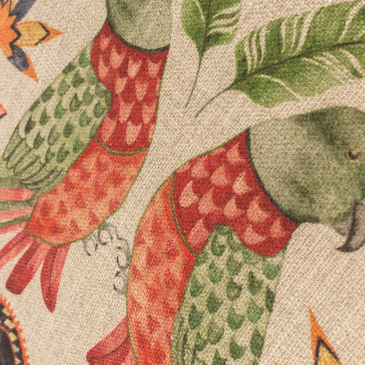 Close-up of the Akamba Animal Linen Cushion showing hand-painted parrots in green and coral plumage with jungle leaf motifs on a natural polyester ground.