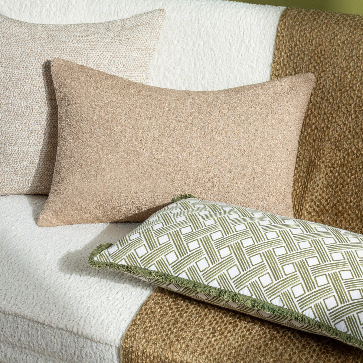 Alexa Reversible Cotton Cushion in olive green basket weave print styled with plain beige cushions on a cream boucle sofa.