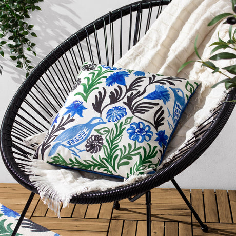 Aljento Abstract Polyester Cushion in blue, square with hand-painted bird and floral print in blue, green and black on white, shown on a black woven outdoor chair.