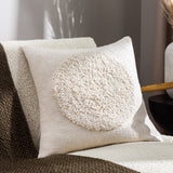 Almo Abstract Cotton Cushion in ecru, woven cotton front with a raised boucle circle motif, styled on a boucle armchair in a living room setting.