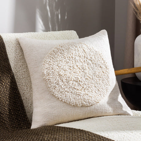 Almo Abstract Cotton Cushion in ecru, woven cotton front with a raised boucle circle motif, styled on a boucle armchair in a living room setting.