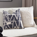 Almo Abstract Cotton Cushion in ecru with a tufted boucle circle on a woven cotton face, shown on a cream boucle sofa beside a patterned grey and cream cushion.