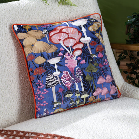 Amanita Abstract Velvet Cushion in cobalt blue with hand-painted mushroom print and orange piping, shown on a cream boucle chair.