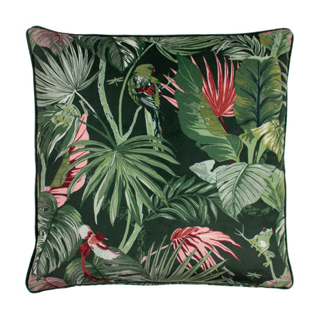 Square velvet cushion in Amazon Creatures Jade print, featuring jungle foliage, a perched bird and a tree frog amid pink blooms on a deep green ground, shown on a white background.