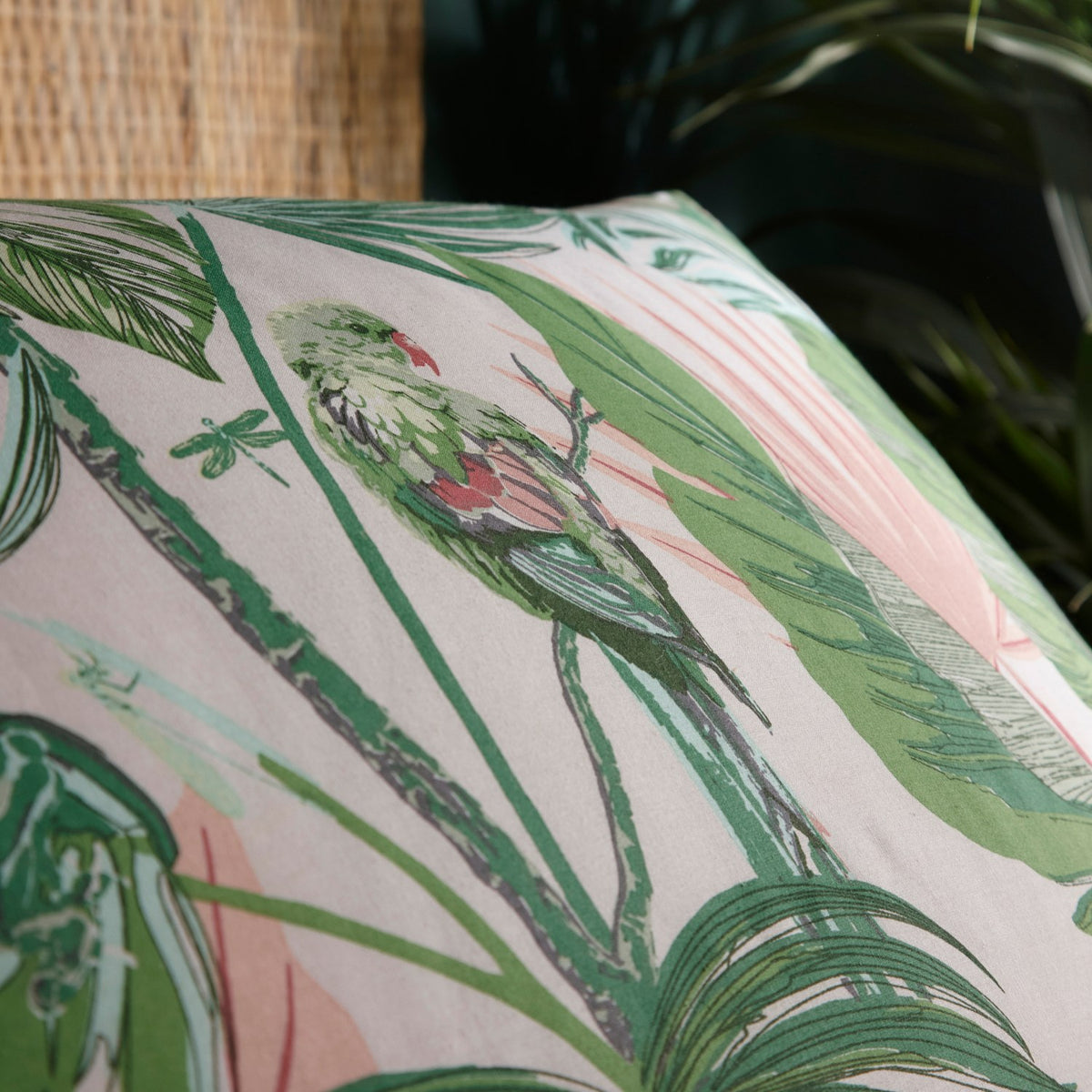 Close-up of the Amazonia Reversible Jungle Duvet Cover in Jade, showing a printed parrot, dragonfly, and palm leaf design in green and pink tones on polycotton fabric.