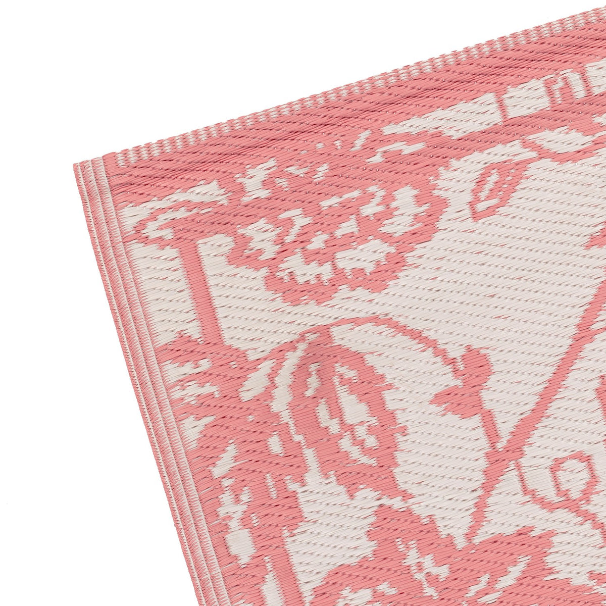 Close-up corner of the Anemone Jacquard Floral Rug, showing a coral pink Jacobean-style floral pattern woven into an off-white ground with a striped edge border.
