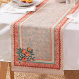 Anemone Floral Polyester Table Runner in multicolour, draped over a dining table with a scalloped coral and terracotta border, botanical ground pattern, and a peach branch motif at the end.