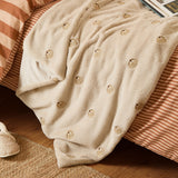 Autumn Pumpkins Velvet Faux Fur Throw in natural beige, draped over a bed with embroidered pumpkin motifs on its plush pile and soft velvet reverse visible.