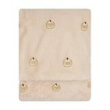 Folded natural beige faux fur throw with plush pile and small embroidered pumpkin motifs scattered across the surface, shown on a plain white background.