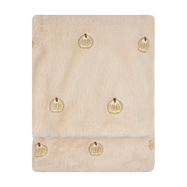 Folded natural beige faux fur throw with plush pile and small embroidered pumpkin motifs scattered across the surface, shown on a plain white background.