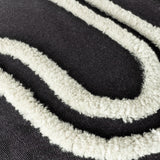 Close-up of the Archie Abstract Cotton Blend Cushion in Mono, showing tufted off-white looped patterns raised against a deep black woven cushion surface.