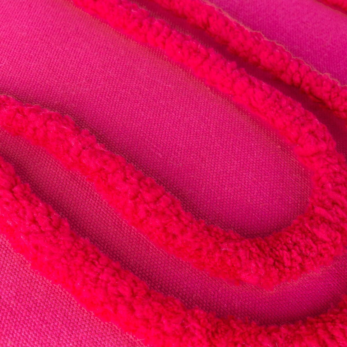 Close-up of the Archie Abstract Cotton Blend Cushion in pink and red, showing tufted looped lines raised against a flat pink cotton blend fabric.