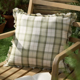 Arrochar Check Linen Cushion in moss green and cream woven tartan with fringed edges, styled on an outdoor wooden chair.