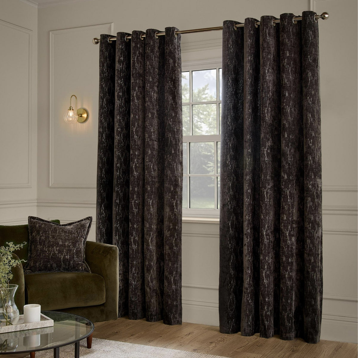 Aurelio Chenille Jacquard fully lined eyelet curtains in charcoal with a subtle abstract woven pattern, shown hanging on a bronze pole in a living room setting.