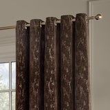 Aurelio Chenille Jacquard Eyelet Curtains in chocolate brown, fully lined with an abstract woven pattern, shown hanging on a bronze-tone pole in a room setting.
