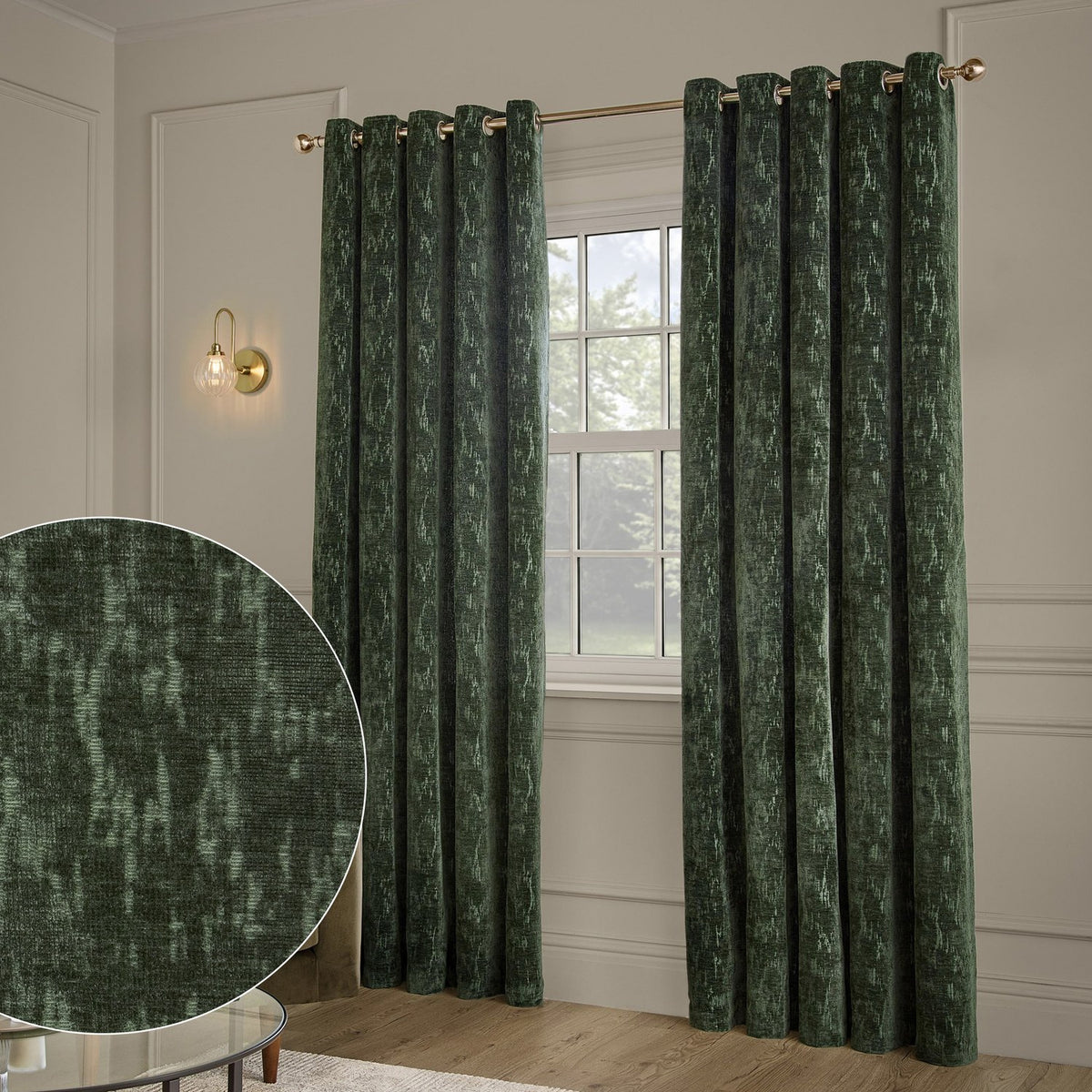 Aurelio Chenille Jacquard Fully Lined Eyelet Curtains in emerald green hang from a brass pole either side of a window, with a fabric texture close-up shown inset.