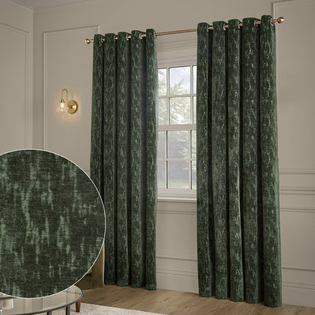 Aurelio Chenille Jacquard Fully Lined Eyelet Curtains in emerald green hang from a brass pole either side of a window, with a fabric texture close-up shown inset.
