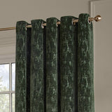 Aurelio Chenille Jacquard eyelet curtains in emerald green, showing brass eyelet rings on a gold curtain pole against a light neutral wall.