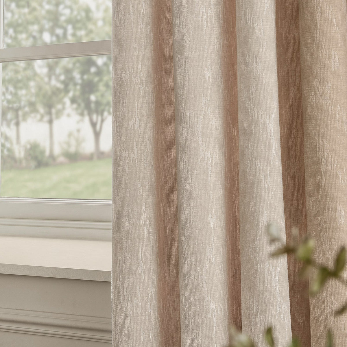 Aurelio Chenille Jacquard Eyelet Curtains in ivory, fully lined with an abstract woven pattern, shown hanging beside a window overlooking a garden.