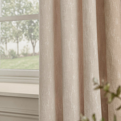Aurelio Chenille Jacquard Eyelet Curtains in ivory, fully lined with an abstract woven pattern, shown hanging beside a window overlooking a garden.