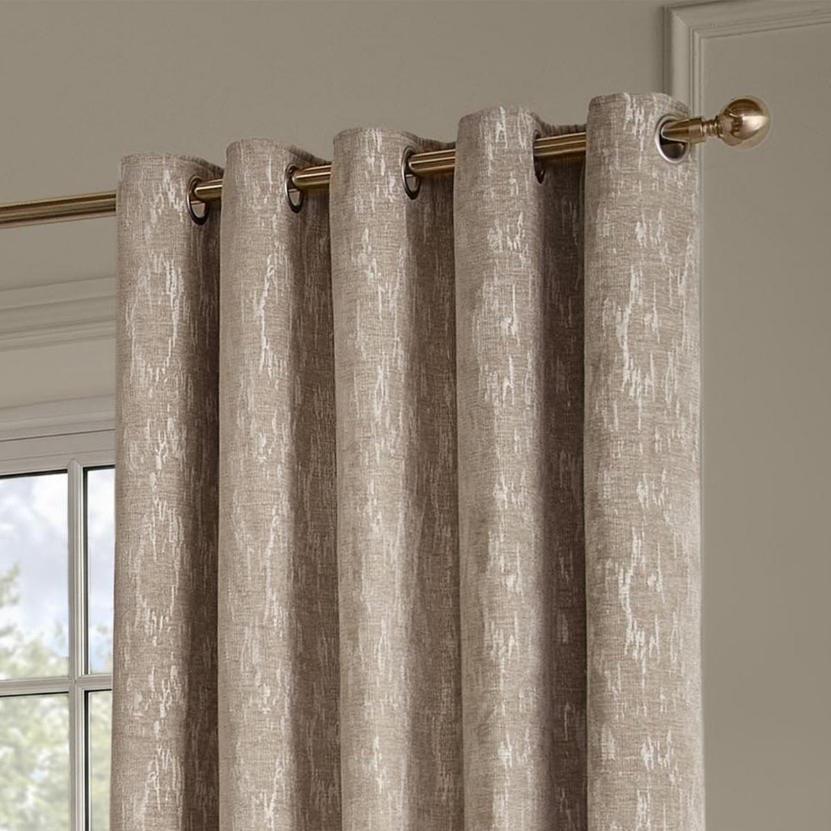 Aurelio Chenille Jacquard Eyelet Curtains in mink, fully lined with metal eyelets on a brass curtain pole, showing a subtle textured pattern in a living room setting.