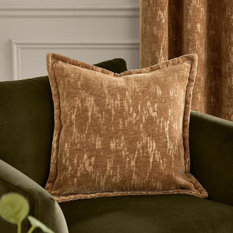 Aurelio Chenille Jacquard Polyester Cushion in caramel with oxford border, styled on an olive green sofa against a matching curtain and panelled wall.