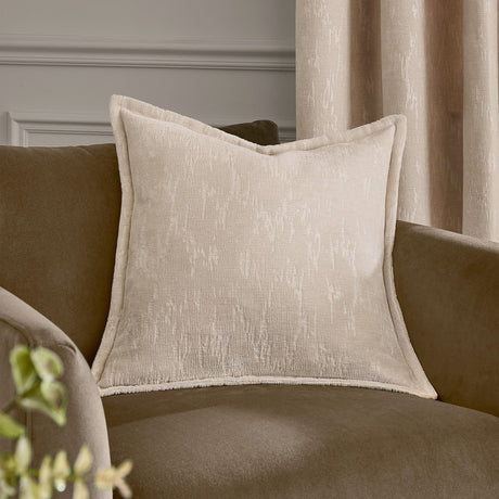 Aurelio Chenille Jacquard Polyester Cushion in ivory with piped edges, shown on a brown sofa in a living room setting.