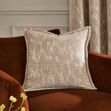 Aurelio Chenille Jacquard Polyester Cushion in mink beige with abstract jacquard pattern and flanged edge, styled on a rust velvet armchair near curtains.