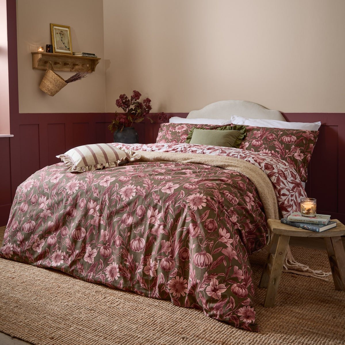 Autumn Garden Reversible Floral Duvet Cover Set in Rose, dressed on a bed with pink and olive green botanical print bedding, layered cushions and a beige throw in a bedroom setting.