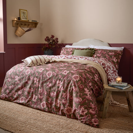 Autumn Garden Reversible Floral Duvet Cover Set in Rose, dressed on a bed with pink and olive green botanical print bedding, layered cushions and a beige throw in a bedroom setting.