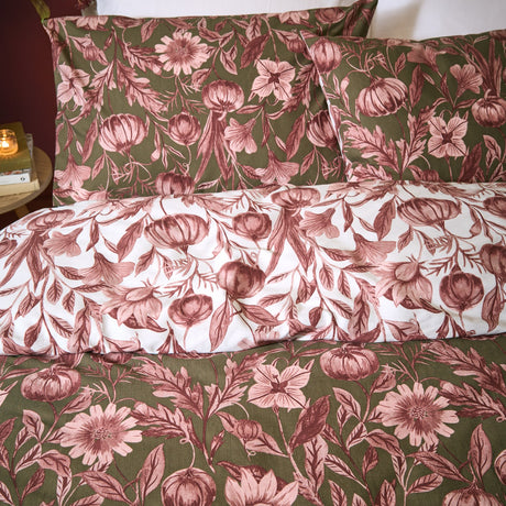 Autumn Garden reversible floral duvet cover set in rose, showing olive green botanical print with pink blooms and pumpkins on one side, reversing to a white ground with matching pillowcases.