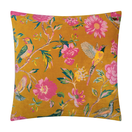 Aviary Velvet Cotton Cushion in gold, a square scatter cushion printed with pink peonies, daisies and perching birds on foliage, shown against a plain white background.