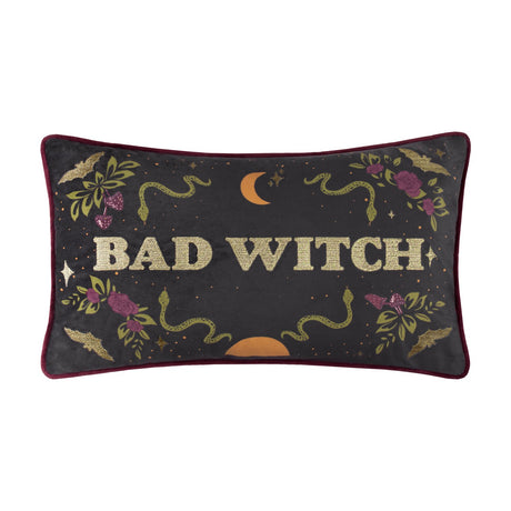 Rectangular velvet lumbar cushion in charcoal with burgundy piping, "Bad Witch" in gold embroidered lettering, surrounded by snakes, roses, bats and a crescent moon, on a white background.