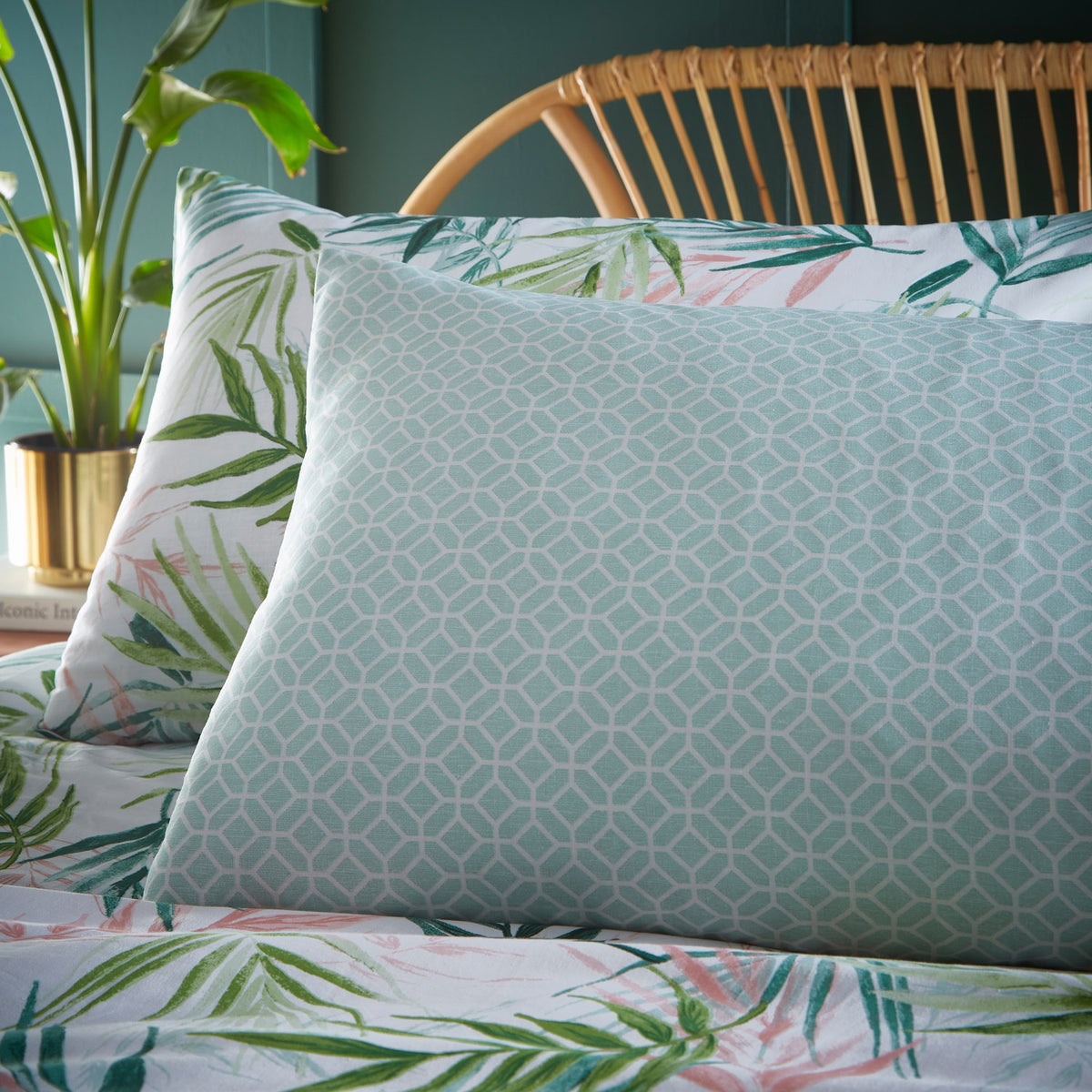Bali Palm Reversible Botanical Duvet Cover Set in green, pillow shown reverse side with aqua geometric print against palm leaf botanical bedding on a bed.