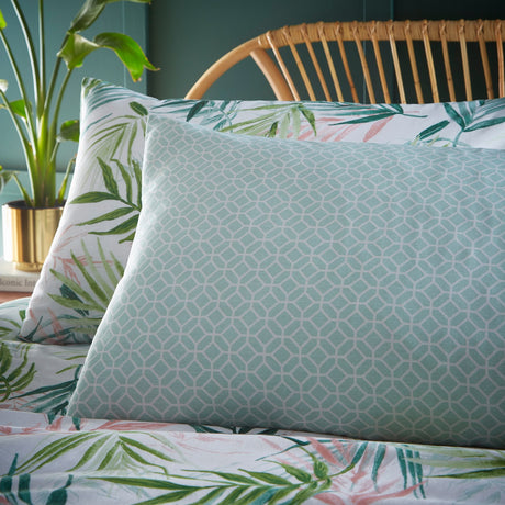 Bali Palm Reversible Botanical Duvet Cover Set in green, pillow shown reverse side with aqua geometric print against palm leaf botanical bedding on a bed.