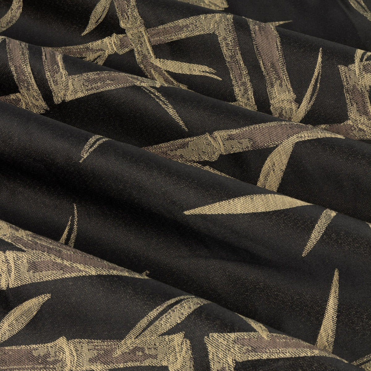 Close-up of black eyelet curtain fabric with jacquard-woven golden-tan bamboo canes and leaves in a loose geometric pattern, showing draped folds and subtle sheen.