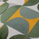 Close-up of the Bardot geometric cut-velvet cushion showing interlocking half-circle pattern in gold, green, blue-grey and off-white tones with a dense, light-catching pile texture.