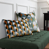 Bardot Geometric Velvet Cushion in gold, green and blue-grey cut-velvet, shown with a matching arch-pattern cushion on a green tufted bench.