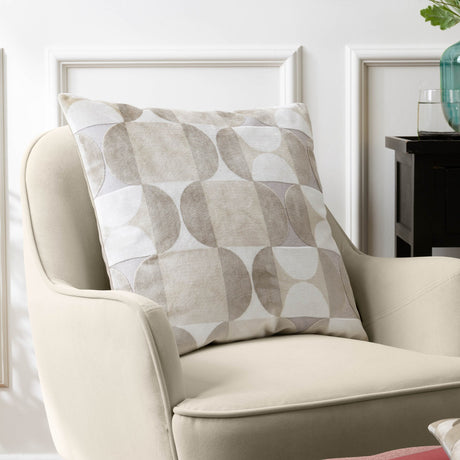 Bardot Geometric Velvet Cushion in Natural, 50 x 50cm square cushion with cut-velvet circle and half-circle pattern in beige, oatmeal and stone grey, shown on a cream armchair.
