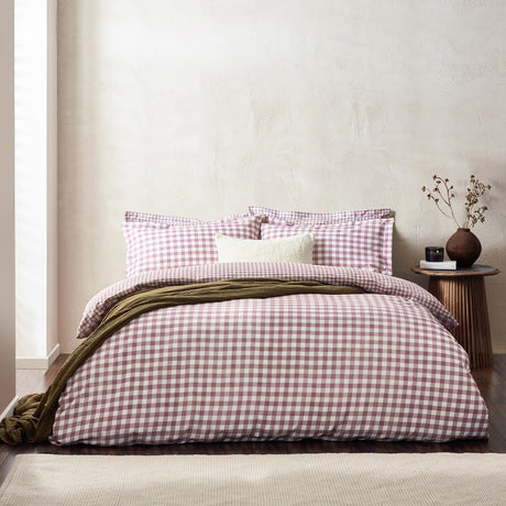 Barton Cotton Gingham Duvet Cover Set in berry pink check on a bed with matching pillowcases, a cream cushion, and an olive throw in a bedroom setting.