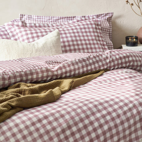 Barton Cotton Gingham Duvet Cover Set in berry, styled on a bed with matching pillowcases, a cream textured cushion, and a mustard throw.