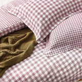 Barton Cotton Gingham Duvet Cover Set in Berry, showing pink and white checked pillowcases and duvet cover with a mustard textured throw folded on the bed.